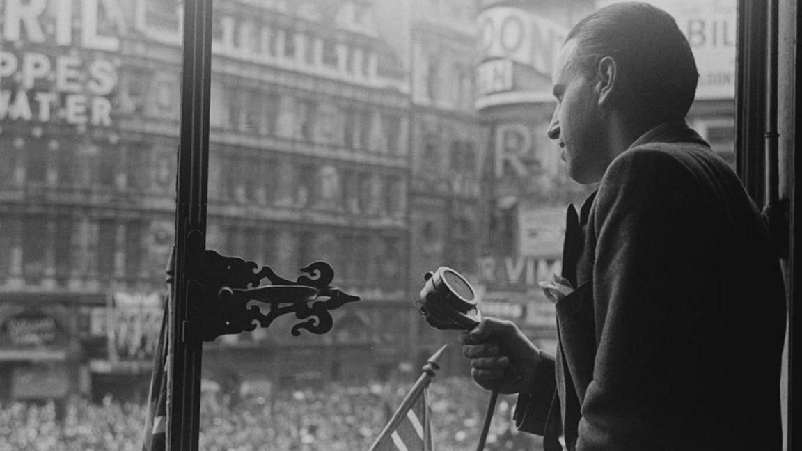 Mr G. Zlatoper, of the BBC Balkans Section, is on a balcony overlooking the joyous crowds in Piccadilly Circus London on 8 May 1945. He is preparing a commentary for the French programmes of the BBC European Service.