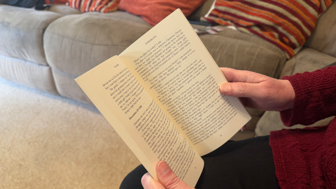 An open book being held in the hands of a woman who is out of shot