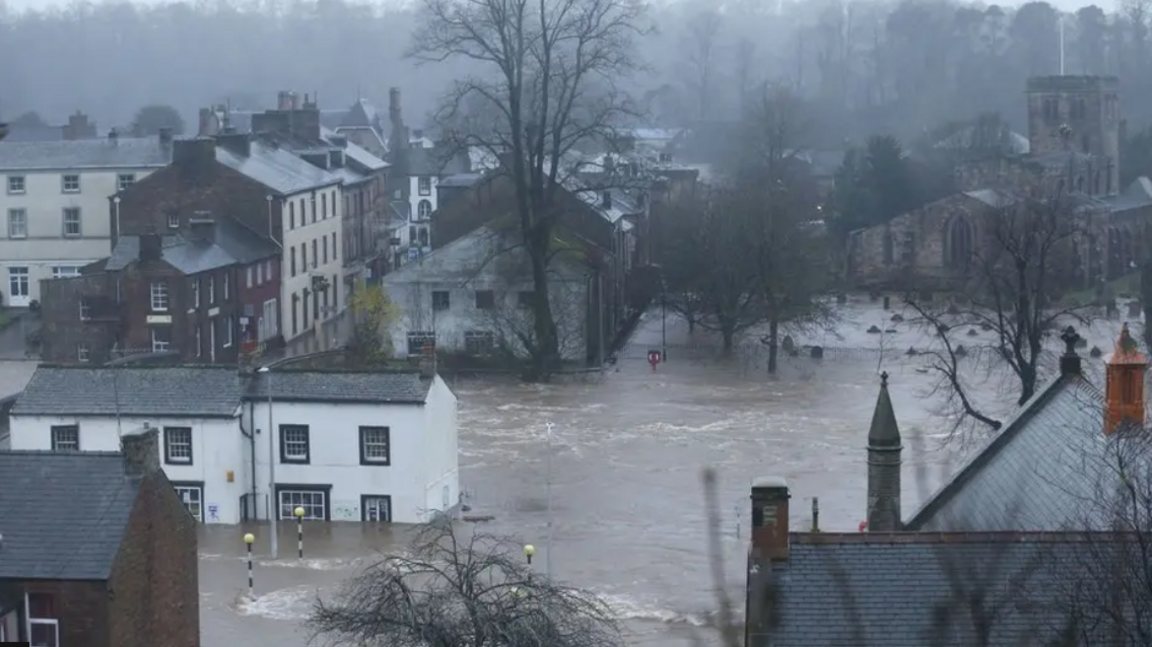 Flood water covers a town square, with water up to the first floor of houses.