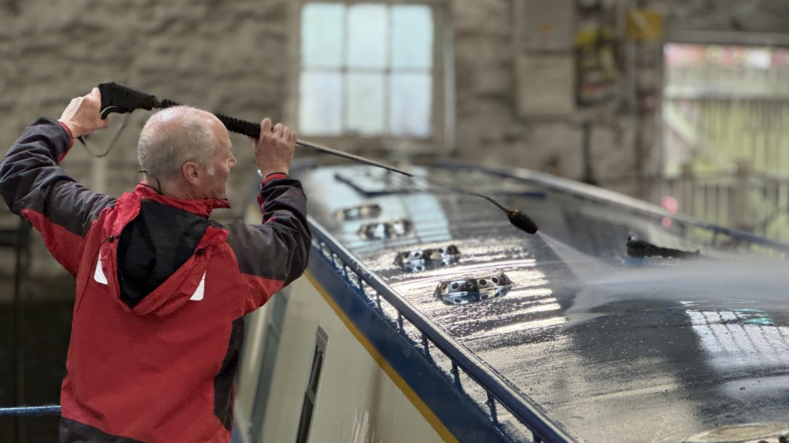 Volunteer Dave Davies pressure washes the boat