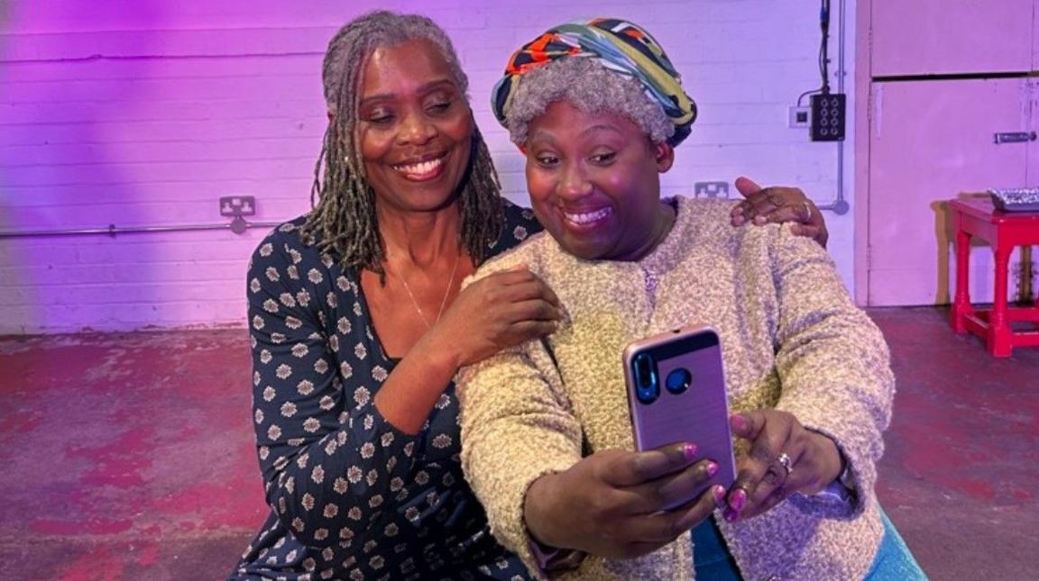 Joan Blaney, with long hair, wearing blue on the left, is pictured with Tonia Daley Campbell, who has a hat on. Both are smiling.