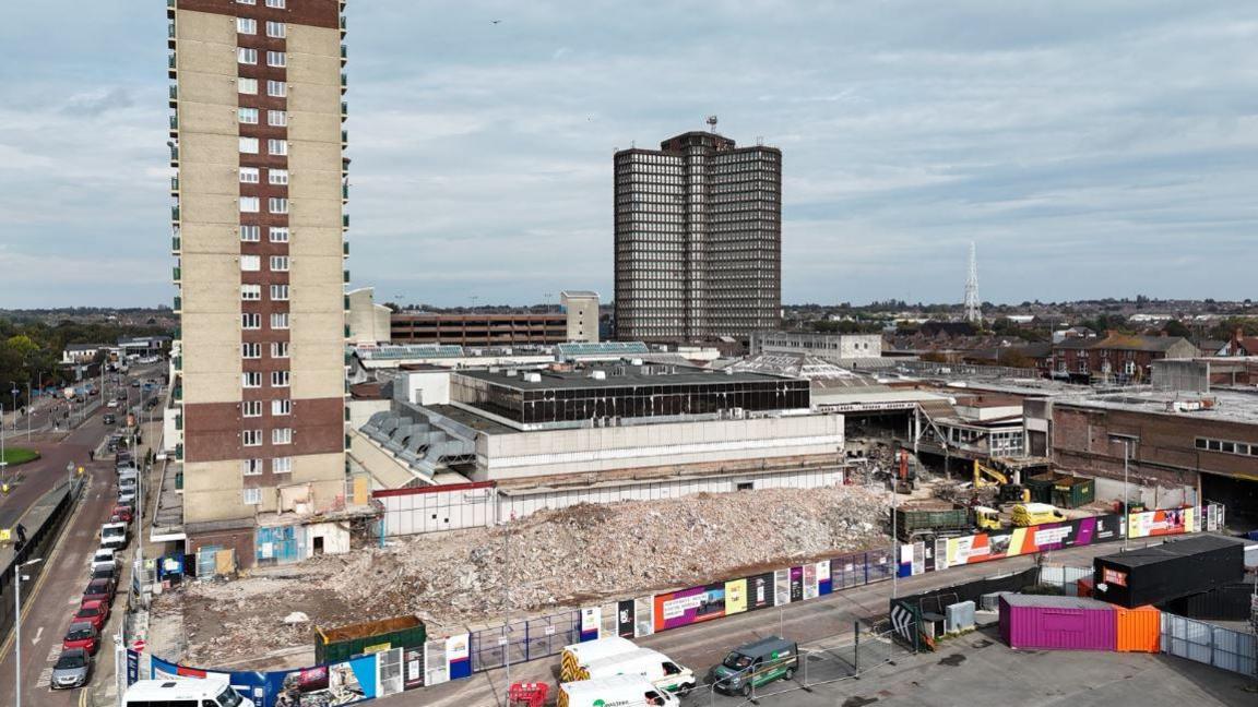 Aerial view of residential high-rise building Strand House towering over Bootle Strand shopping centre demolition site.