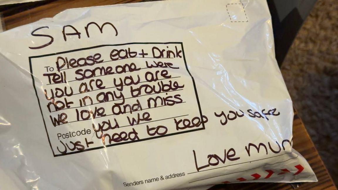 A parcel. On the front is written: "Sam, please eat and drink. Tell someone where you are. You are not in any trouble. We love and miss you. We just need to keep you safe. Love mum."
