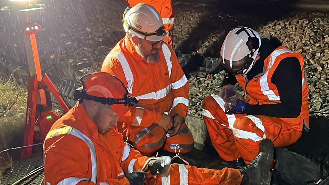 Signalling engineers fixing damaged cables overnight at Stevenage, the are seen wearing high vis orange clothing 