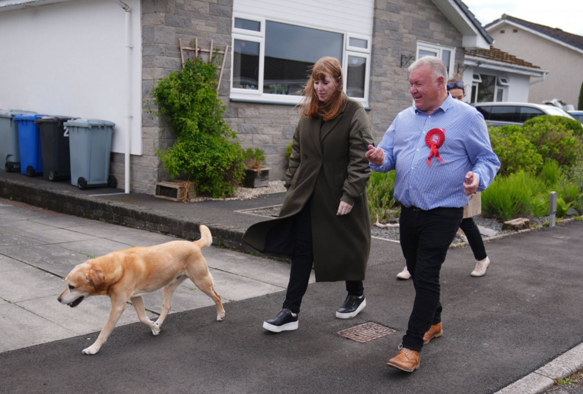 Davy Russell in a blue shirt alongside a woman with red hair in a long coat with a Labrador dog walking on a residential street