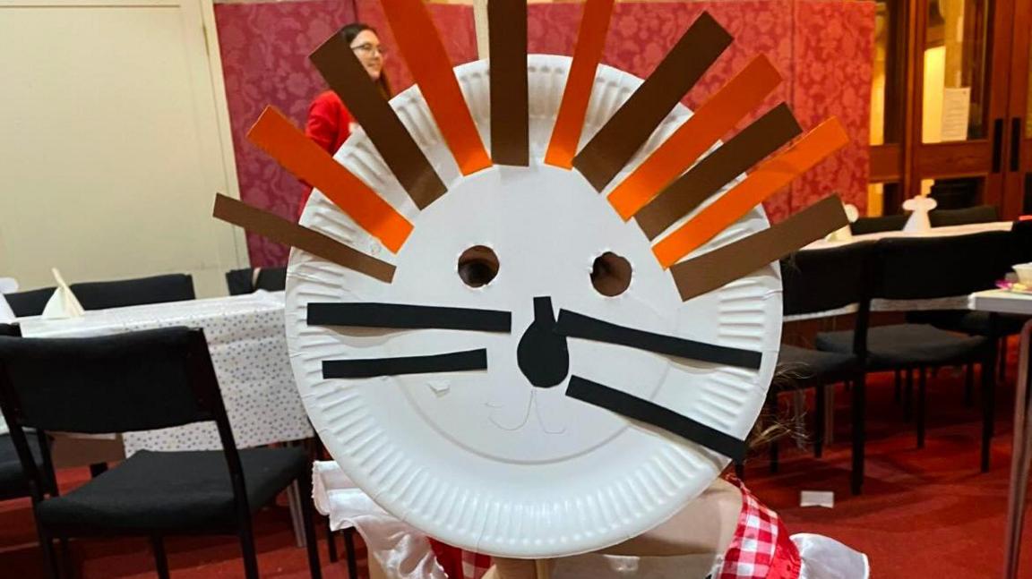 One of the children that attends hygge church with a lion mask made at one of the craft sessions. The mask is made from a paper plate. 