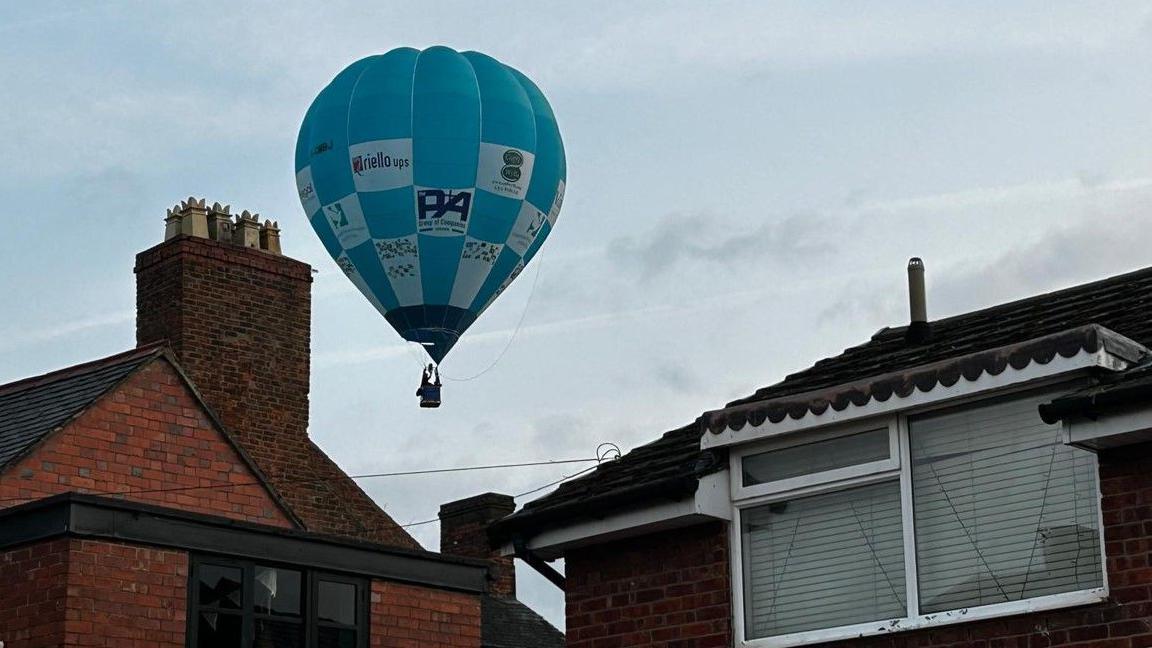 A hot air balloon is seen in the background in the image, between two buildings in the foreground in the photo.