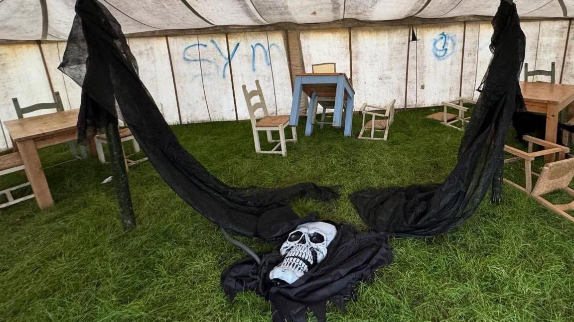 A ghostly apparition laying broken on the floor inside a tent in the daylight