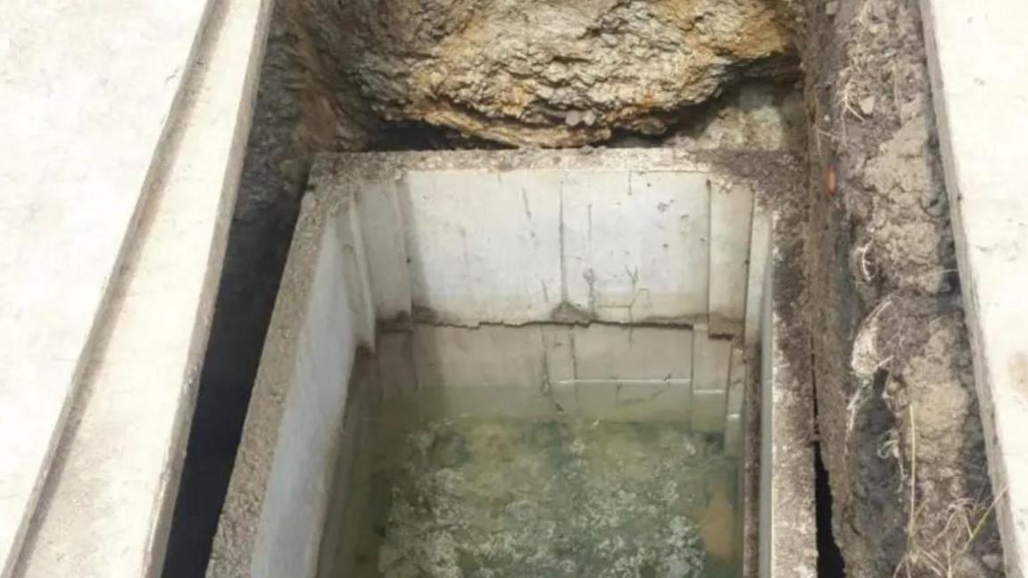 A picture of an open concrete vault which is filled with floodwater.