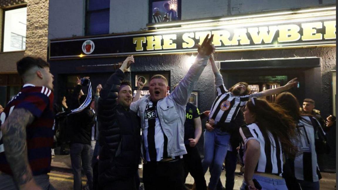 Fans run around the street outside the Strawberry pub after winning the cup