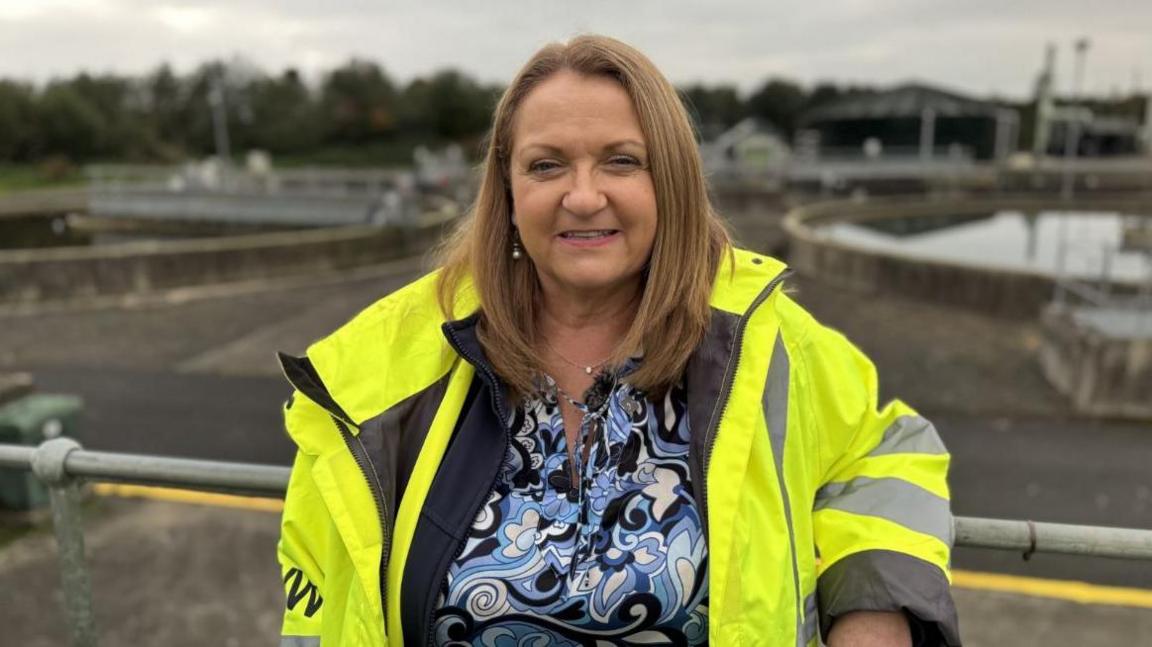 Angela Halpenny of NI Water, a woman in yellow jacket, with long blonde hair and blue shirt with swirls.