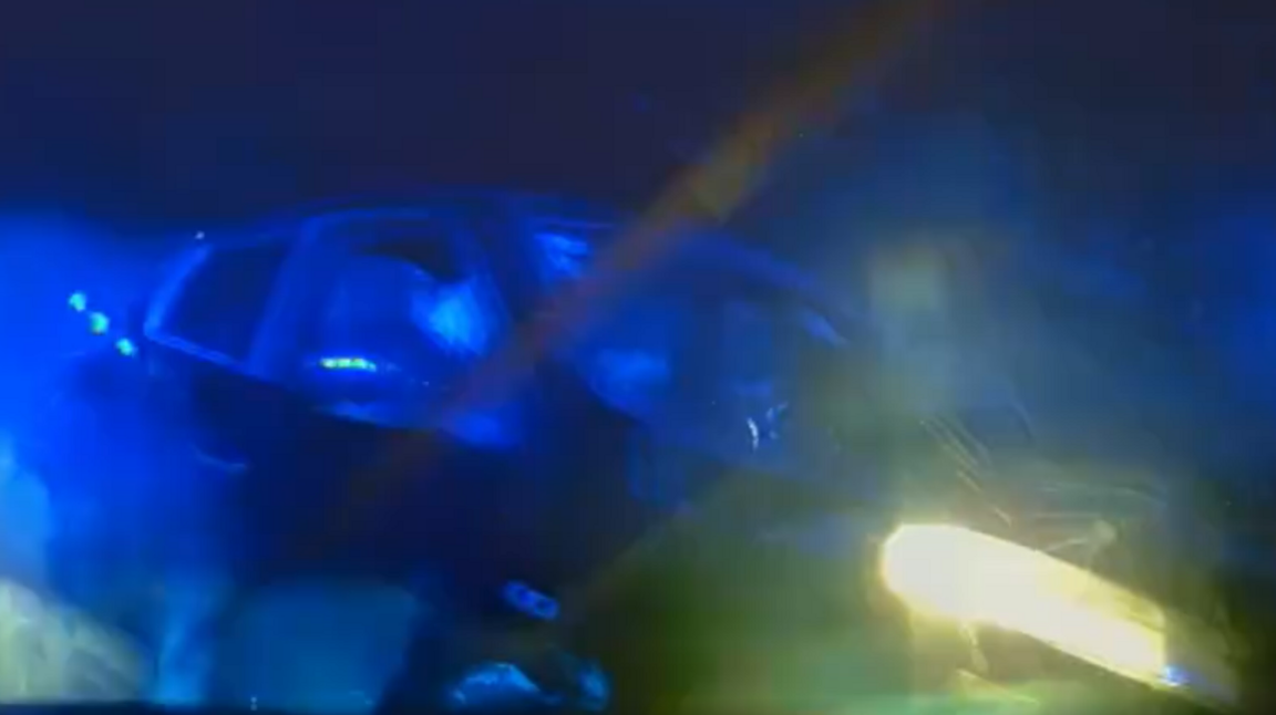 A blurry police dash cam image of a black car.