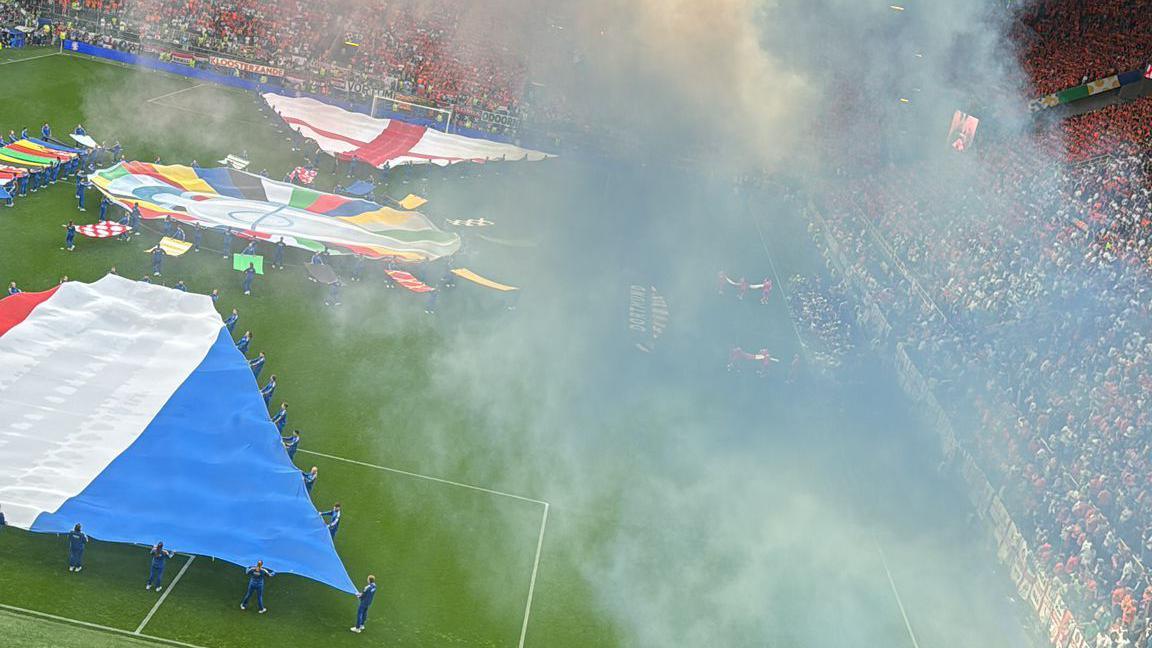 A shot of the pitch with people holding the flags of England and the Netherlands