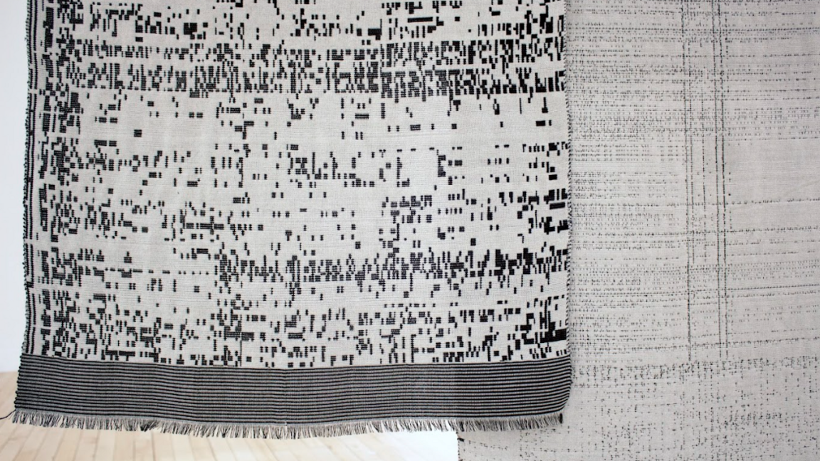 Picture of two tapestries being shown in this year's Biennial. They've woven in white, grey and black threads and hang from the wall in the museum. 