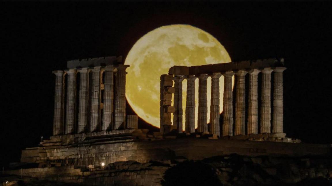 Strawberry Moon rising over the ancient Greek temple of Poseidon on Cape Sounion, near Athens