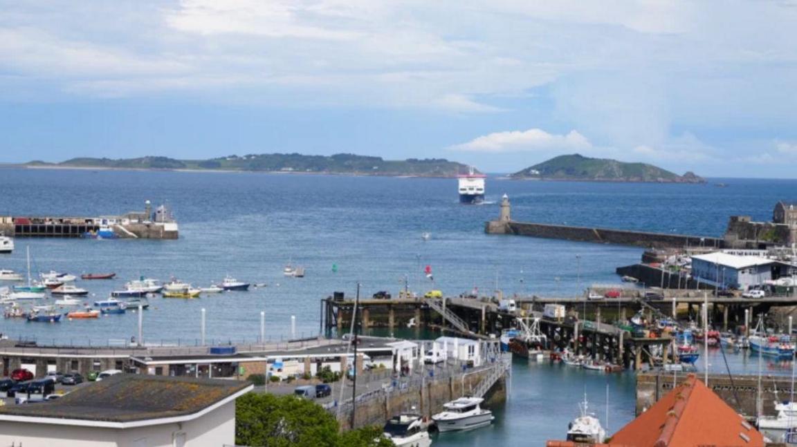 The coast off of Guernsey. There is a large body of water with boats visible.