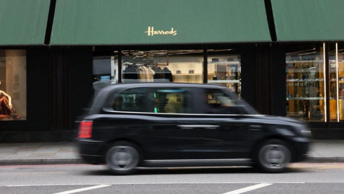 File image showing a black cab driving past Harrods department store in central London