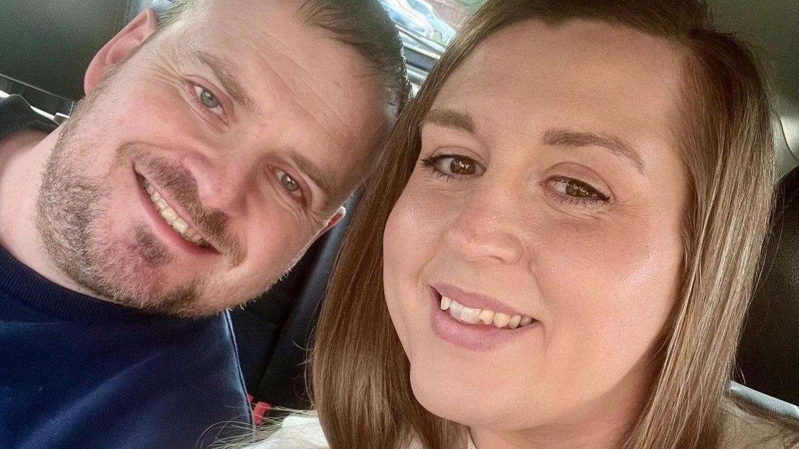 Ben Link with a short cropped beard and short light brown hair smiling at the camera, with Lydia Collins, with shoulder-length light hair, also smiling at the camera