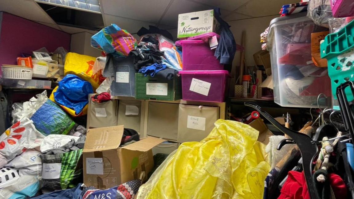 Boxes and bags of clothes in a small room.