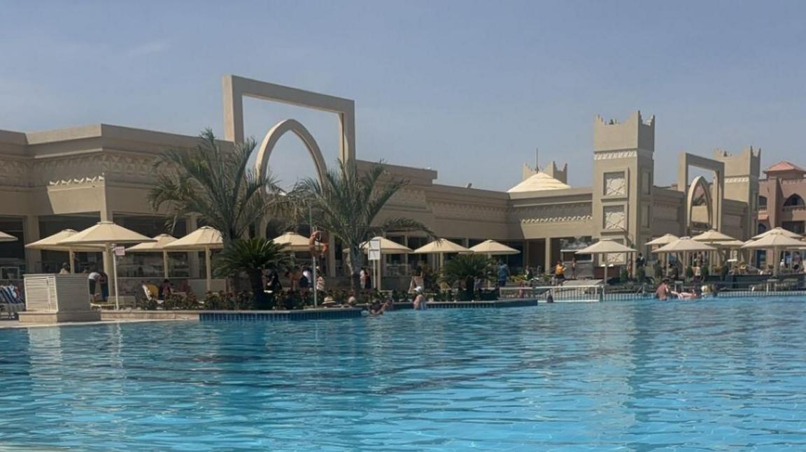 A pool with umbrellas and lounge chairs. 