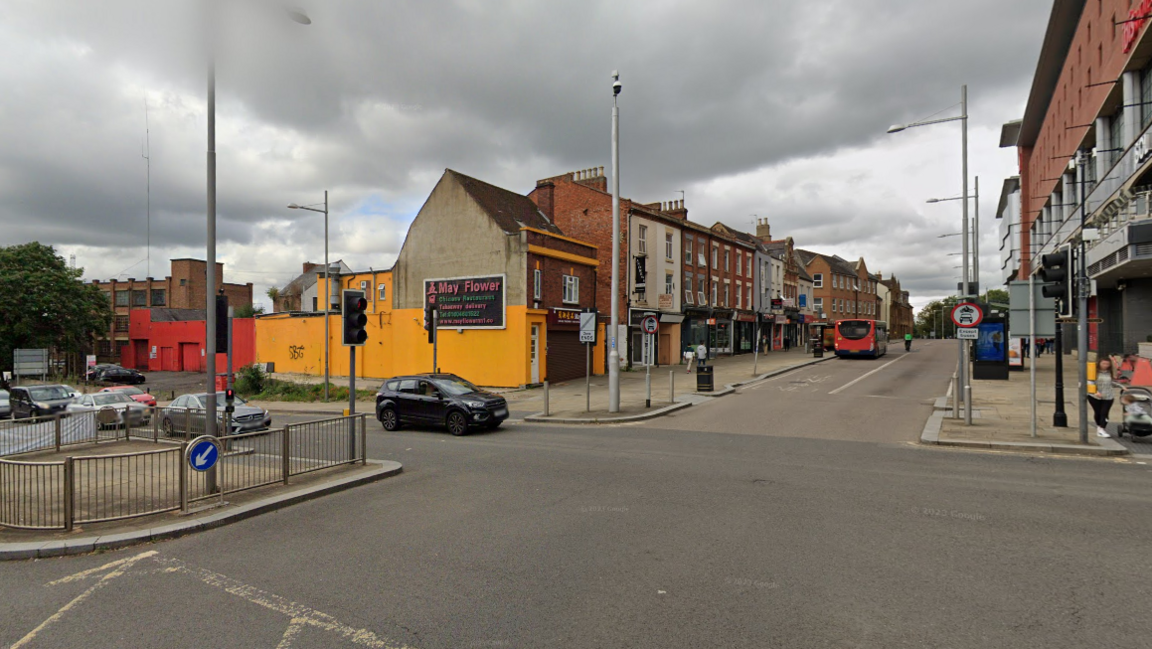 Traffic junction showing a street, traffic lights, a pedestrian island, and buildings either side, include a Vue cinema 