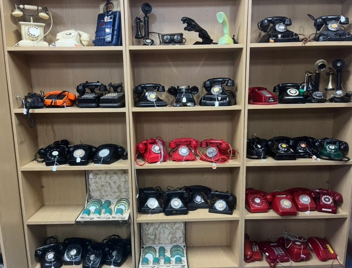 Phones are on shelves over five levels, with at least eight phones each on most levels. Many of them are red or black.