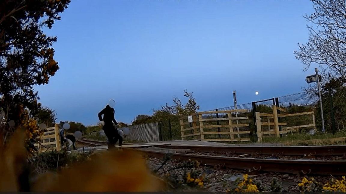 Dealbh bho Network Rail a' sealltainn dhaoine òga air an loidhne rèile