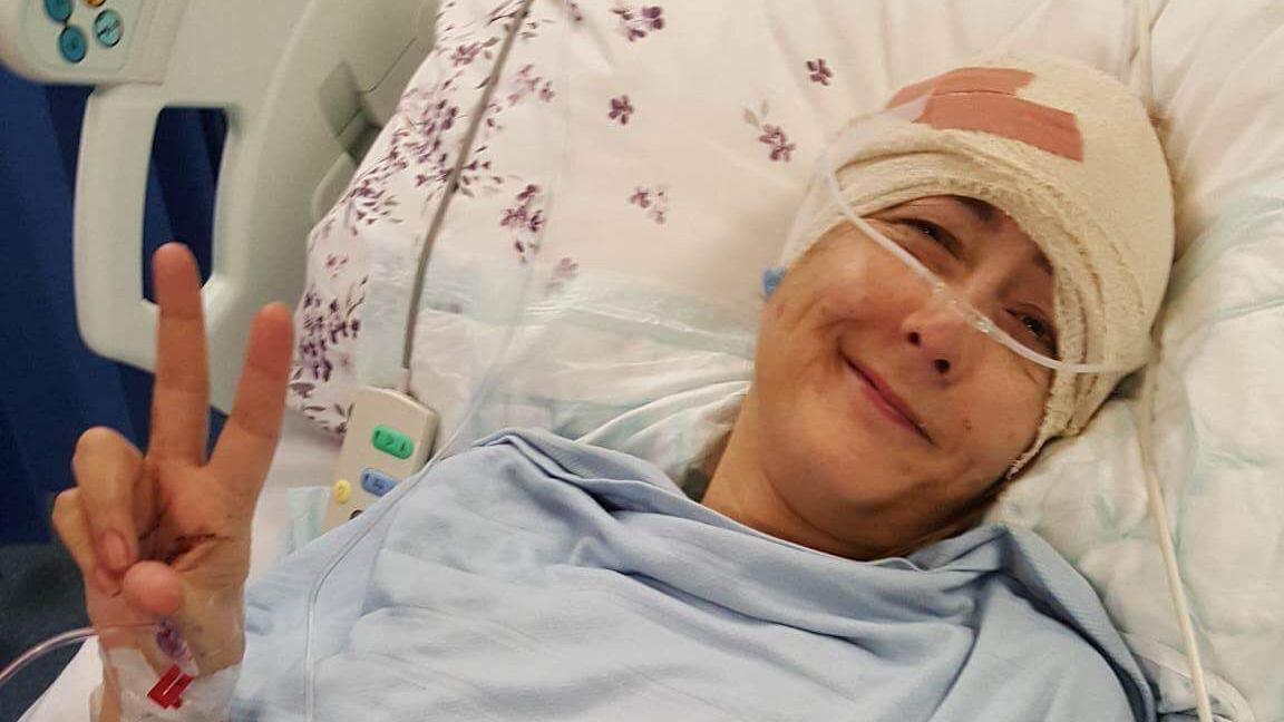 Nikki Gilmour in a hospital bed with a bandaged head after surgery