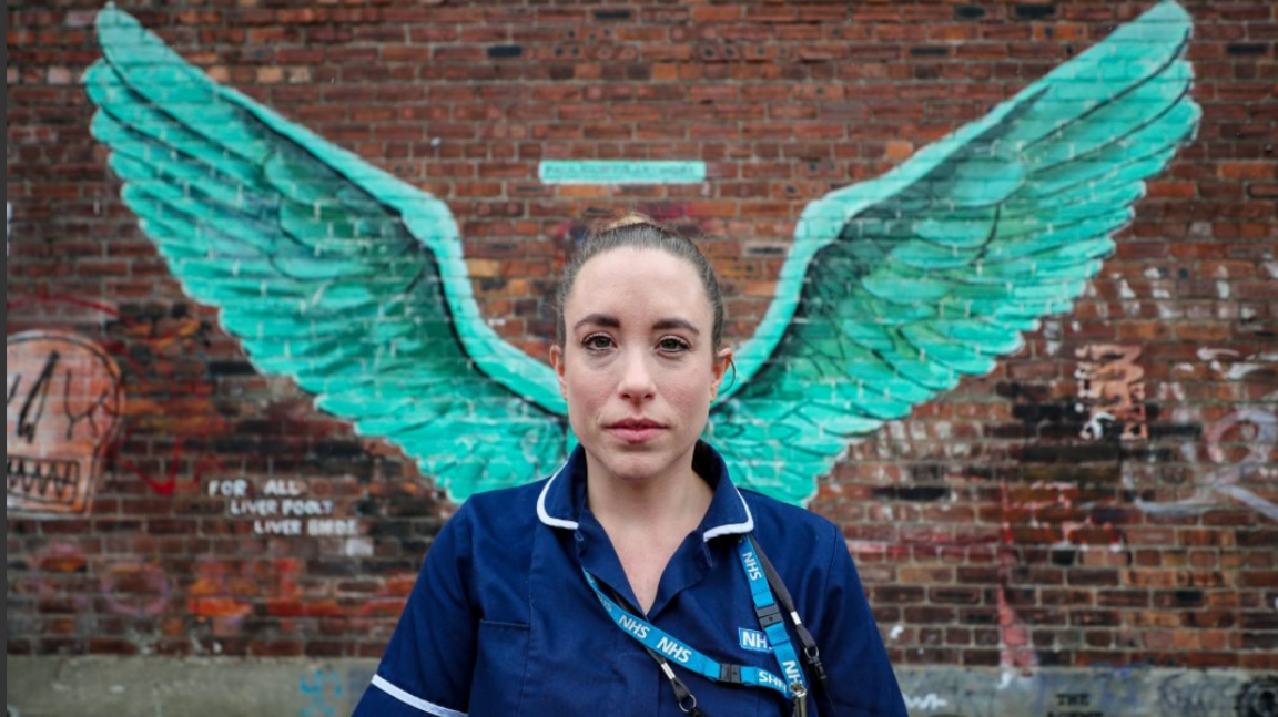 District nurse Erica Daly stands in front of wings painted on brickwork