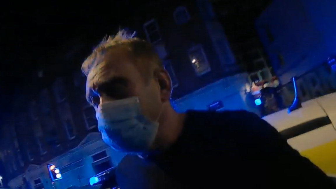 A man wearing a face mask being arrested.