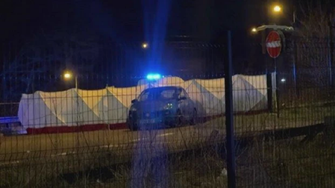 A car is parked outside a large white forensic tent, on the road.