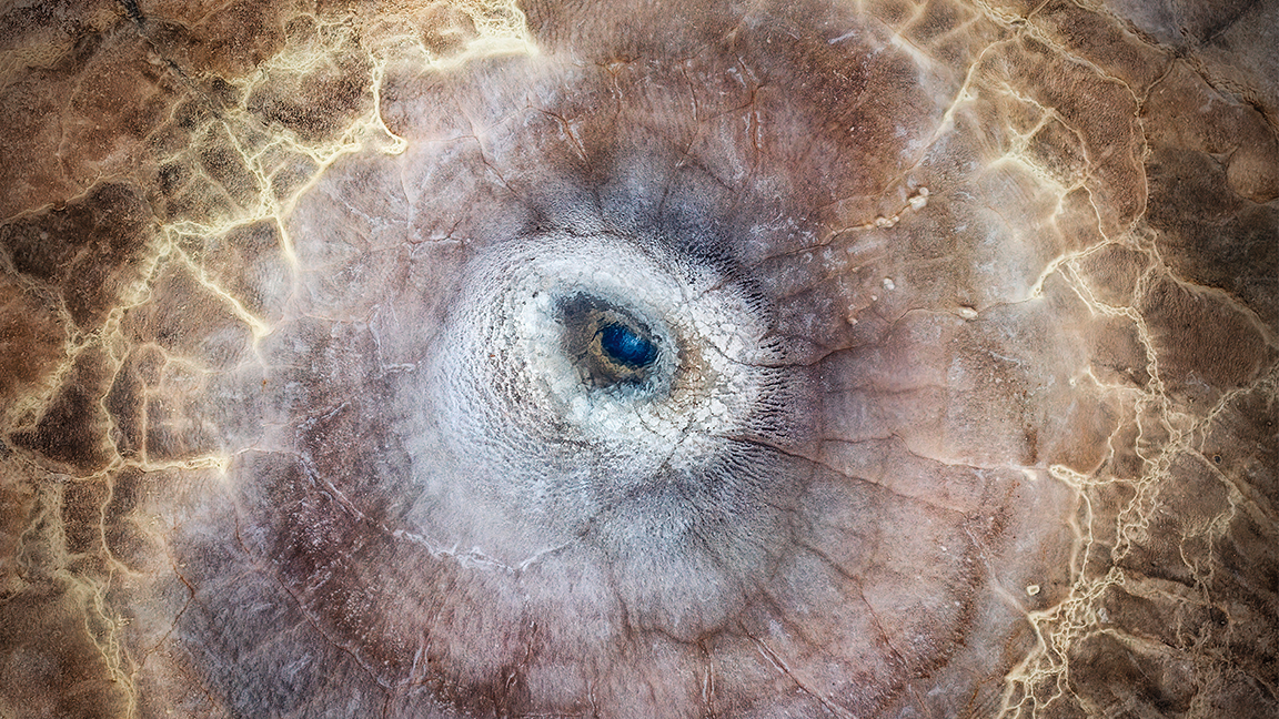 The camera hovers over a geothermal pool that mimics the form of a dragon’s eye, its deep, sapphire-blue centre acting as the ‘pupil’ of this mythical creature’s gaze
