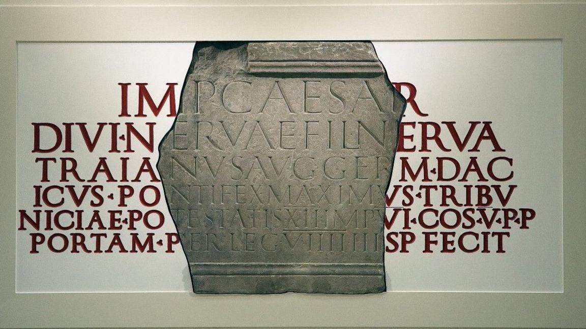 A large fragment of a Roman inscription, mounted on a reconstruction of the entire text