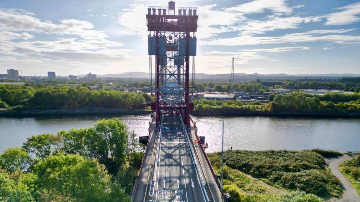 The Newport Bridge spanning the River Tees. Trees line either side of the water.