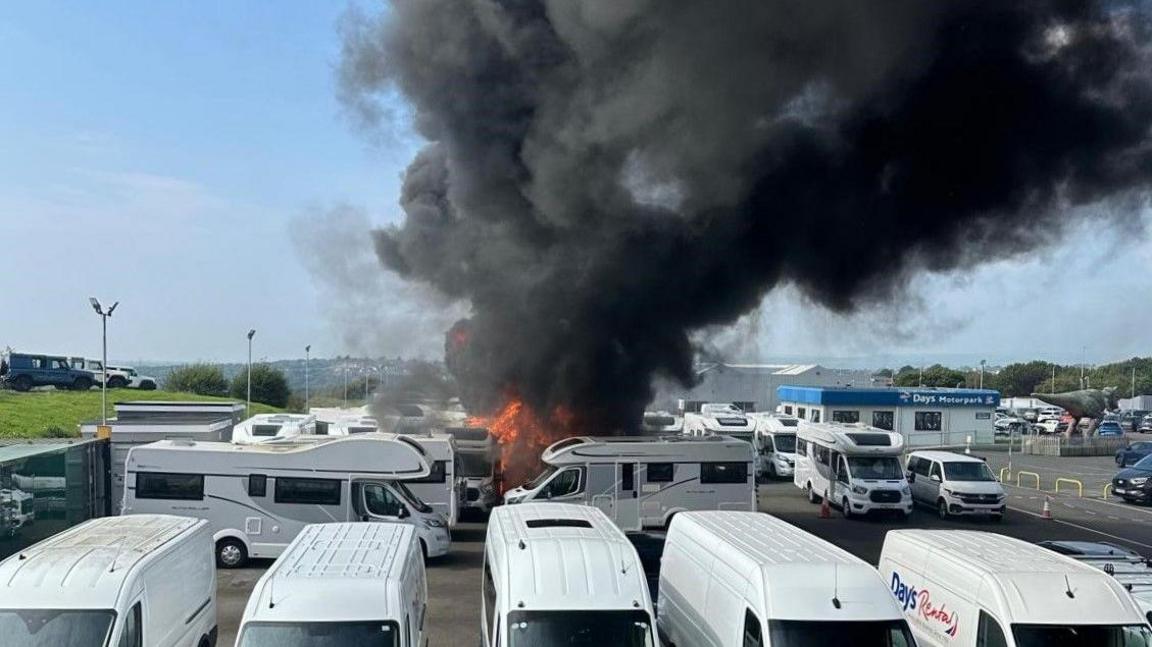 Black smoke billows into the sky in a blaze that wrecked vehicles