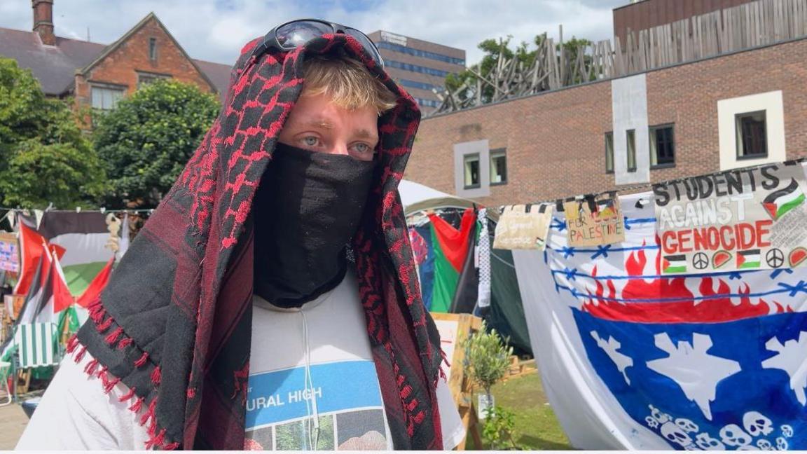 The spokesman standing in front of the encampment. He covers the bottom part of his face