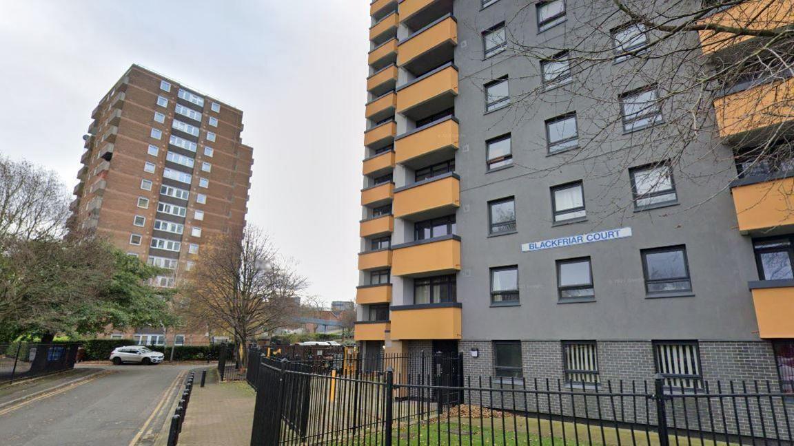 A view of Salford apartment block Blackfriar Court, including a sign identifying the block, with a separate apartment building in the background. 