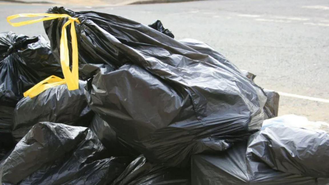 File image of a pile of black bin sacks with yellow tie handles on a street