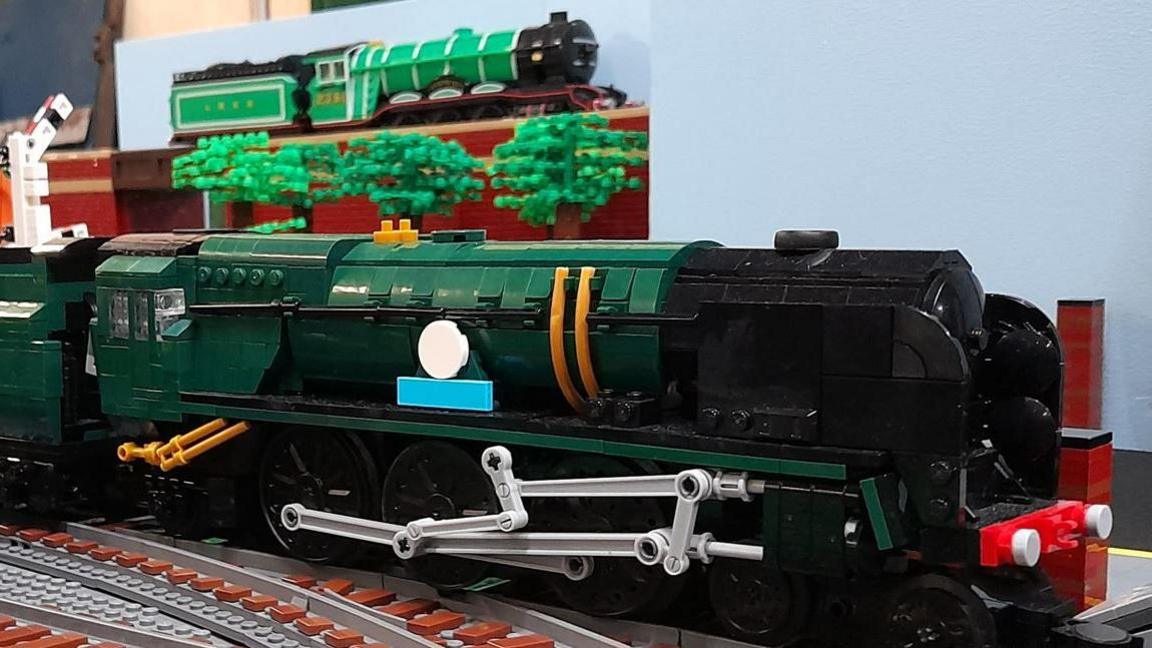 A green and black Lego locomotive on the tracks