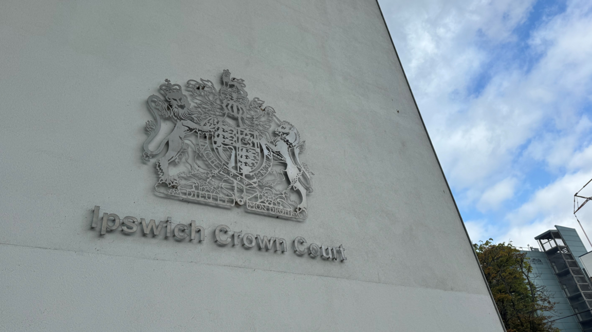 The metal Ipswich Crown Court crest displayed on a white block of concrete at Ipswich Crown Court.