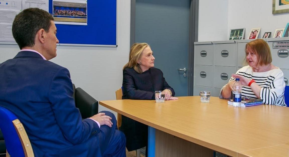 Three people sitting at a desk mid conversation