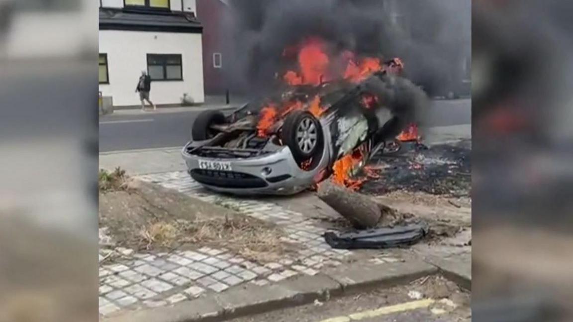 A car on its roof burning after it was set on fire during unrest.