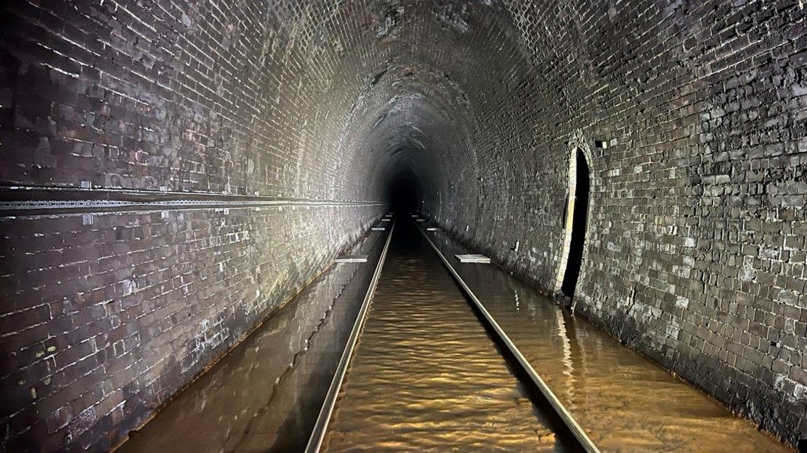 Brown coloured floodwater on the tracks of the Bransty tunnel.