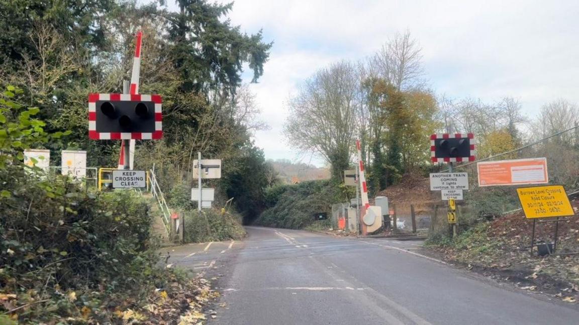The level crossing at Burrows Lane, where the road runs over the railway. The gates are open in the picture.
