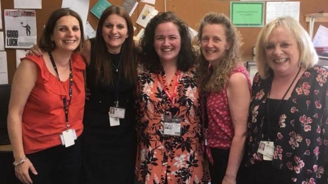 Five women huddled together in a classroom all smiling - (left to right) teachers Sam Kerr and Heidi Curry, with former pupil Jessica Gunning, teacher Helen Ingham and Gunning's mum, Val Gunning.
