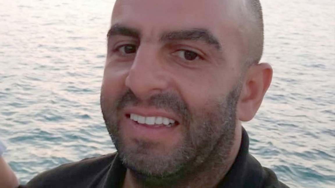 Samir Zitouni is smiling at the camera in a close-up shot of his face. He is balding and has a moustache and a beard