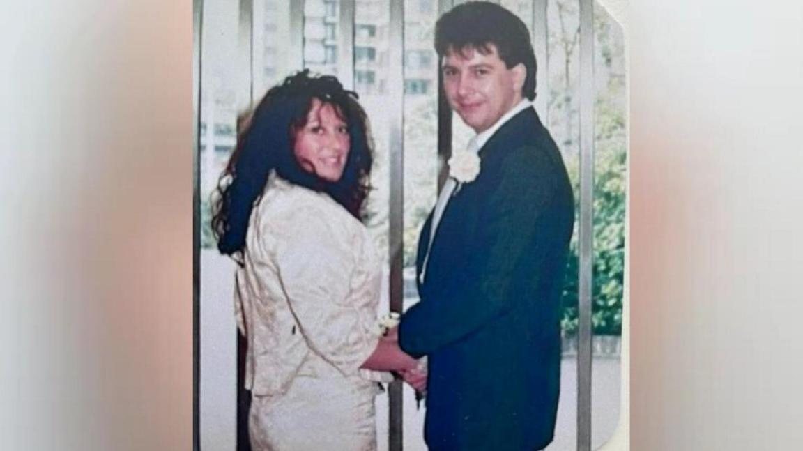 A weeding picture of Paul and Val Unwin. He is wearing a blue suit and button hole and she is wearing a cream suit