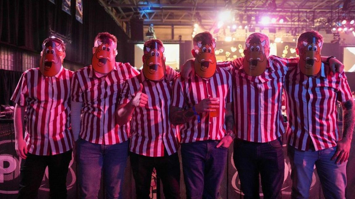Six people are wearing the same type of mask and a red and white striped top.