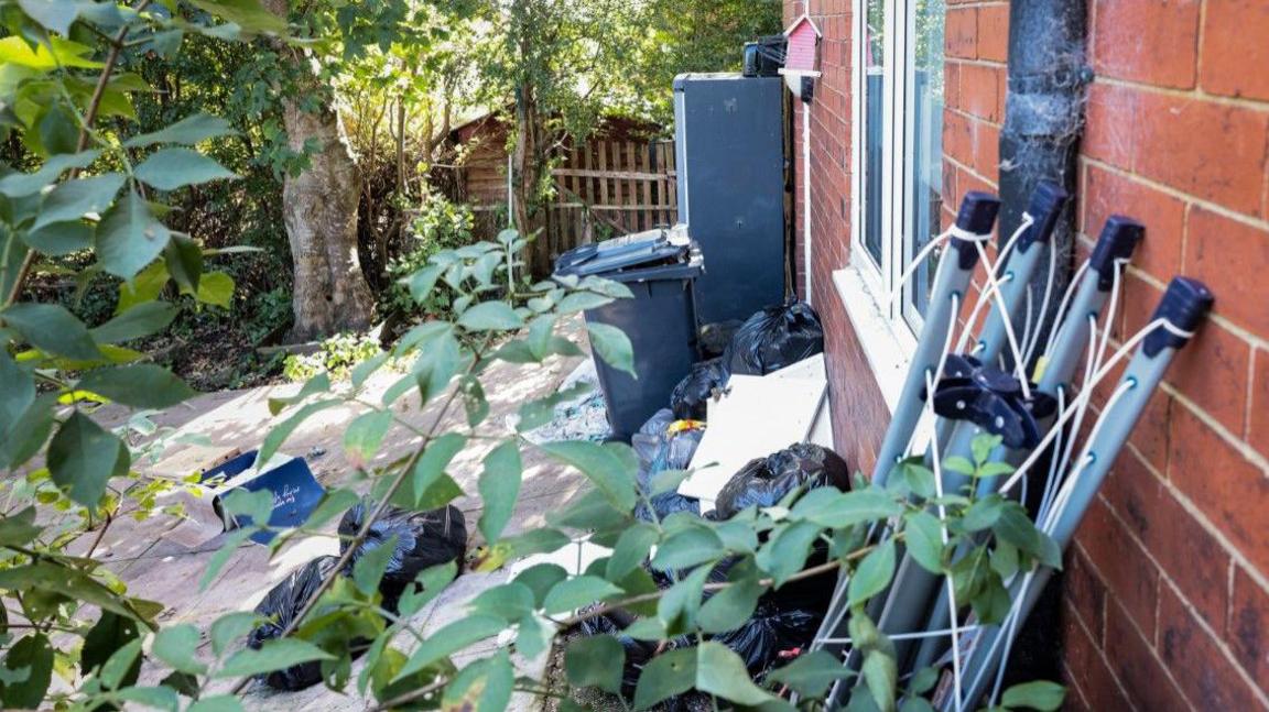 Piles of litter outside a house leaning against the wall