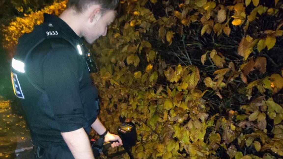 Police officer checking bushes